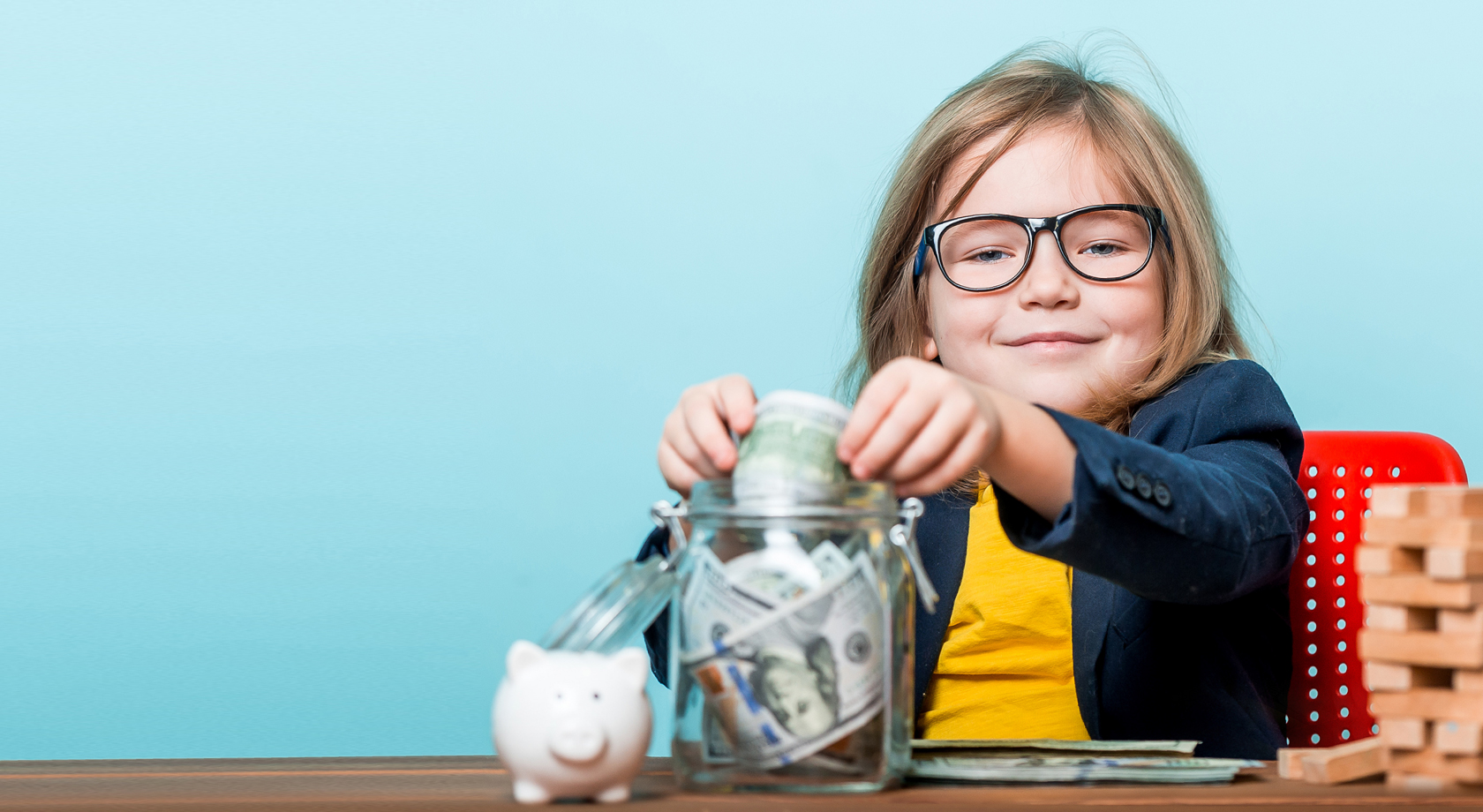 Child putting money in a savings jar. 